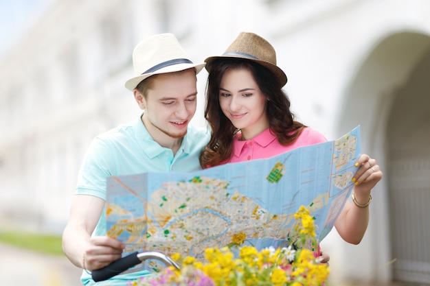 Young couple using a map and riding a bicycle in the city