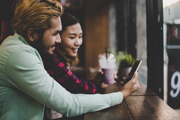 Photo young couple using phone in cafe