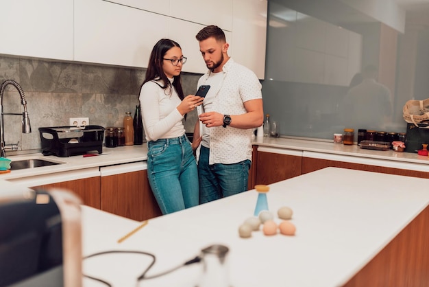 A young couple using a smartphone while thinking of what to cook