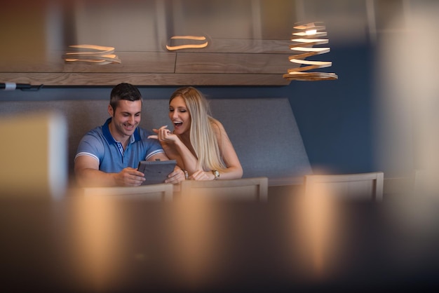 Young couple using tablet computer at luxury home together, looking at screen, smiling.