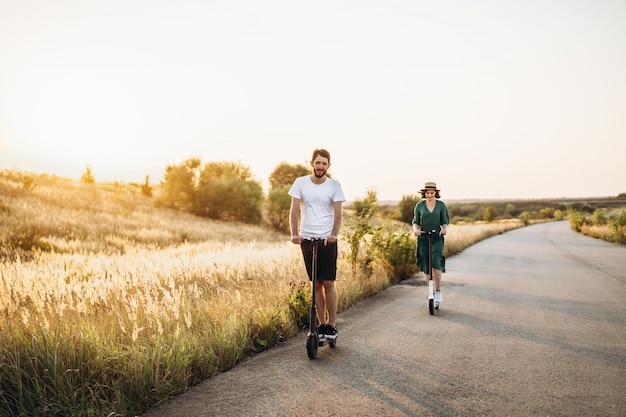 Young couple on vacation having fun driving electric scooter on the road in the countryside. Content technologies. Copy space