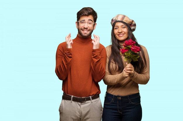 Young couple in valentines day crossing fingers for having luck