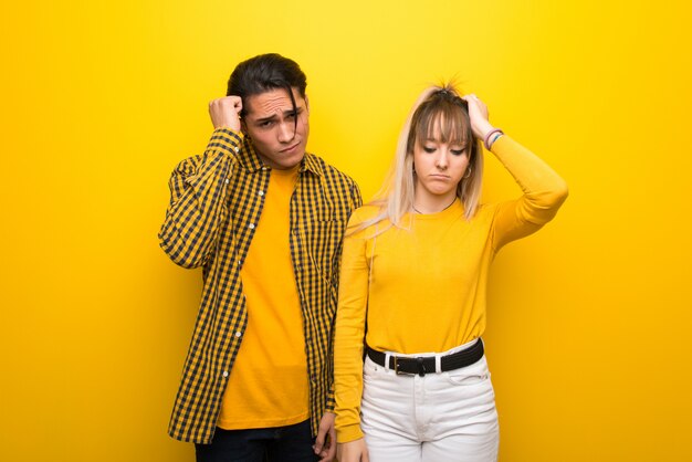 Young couple over vibrant yellow background with an expression of frustration