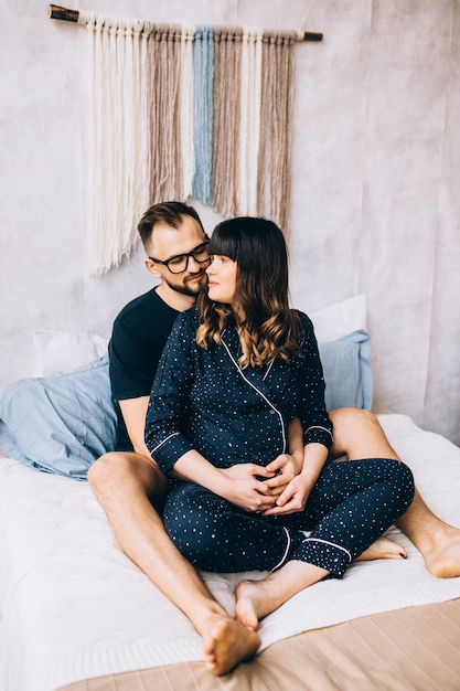 A young couple waiting for a baby sitting on a bed