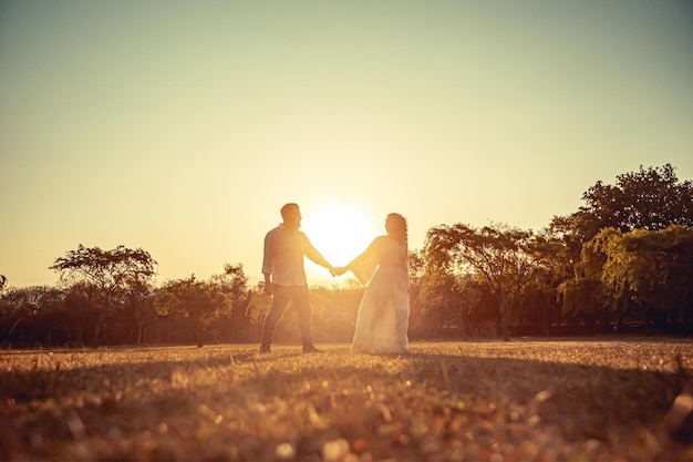 Young couple walking in the field in the middle of sunset