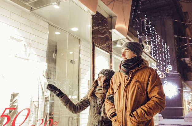 市内中心部を歩いている若いカップルと夜のウィンドウショッピング。