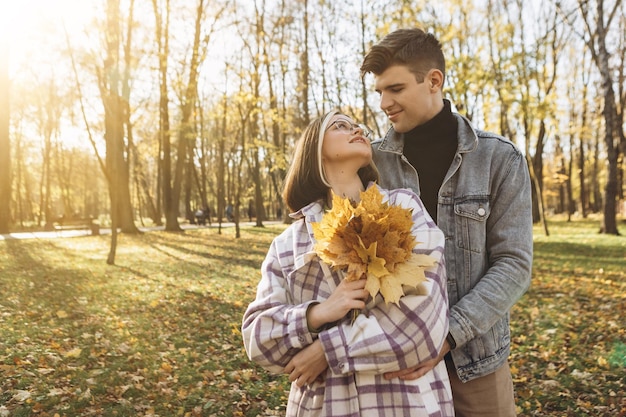 young couple walking outside park hugging smiling kissing laughing spending time together autumn
