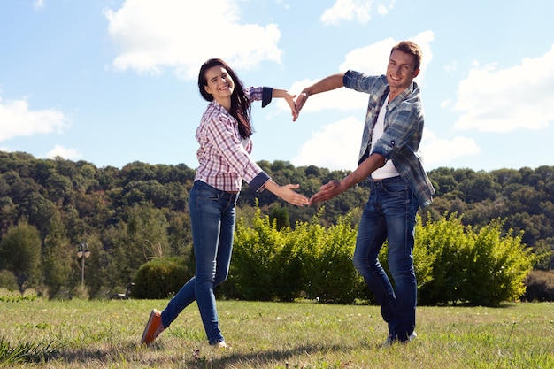 young couple walking in the park and making a heart symbol with their hands