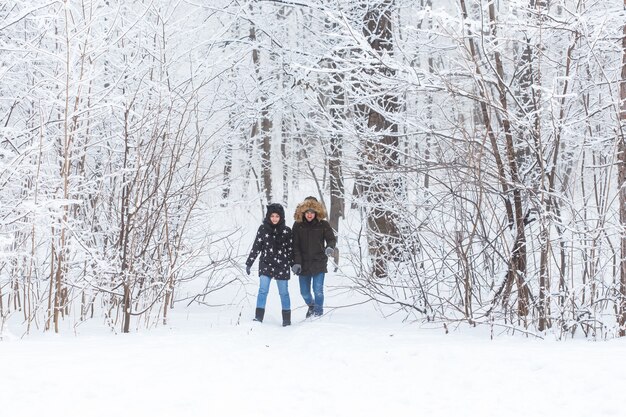 雪に覆われた公園を歩いている若いカップル。冬の季節。