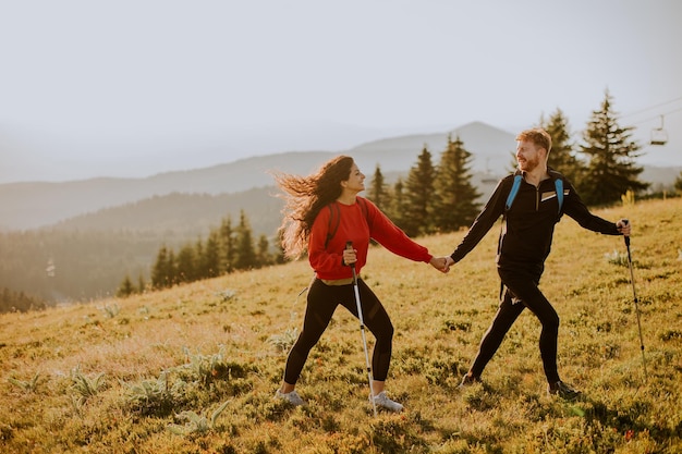 Young couple walking with backpack over green hills