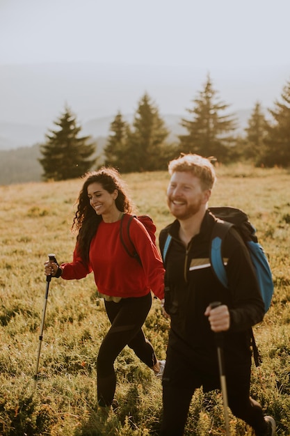 Young couple walking with backpack over green hills