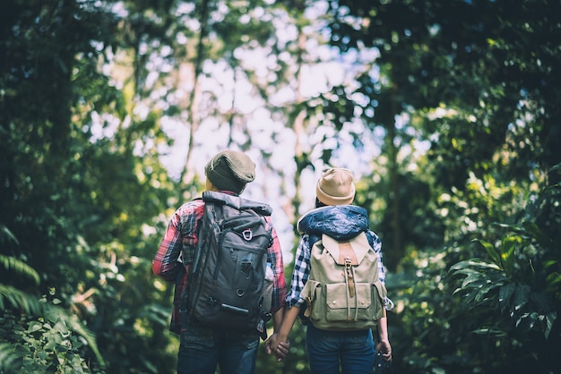 Young couple walking with backpacks in forest