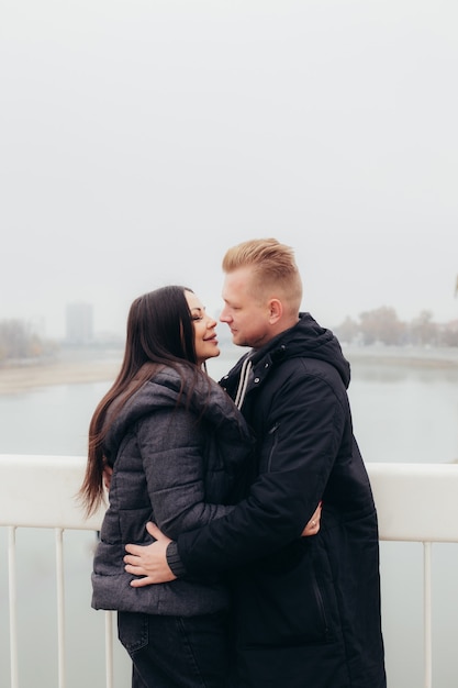 A young couple in warm clothes hugs and looks at each other