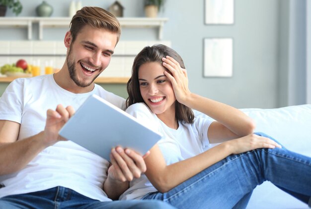 Young couple watching media content online in a tablet sitting on a sofa in the living room