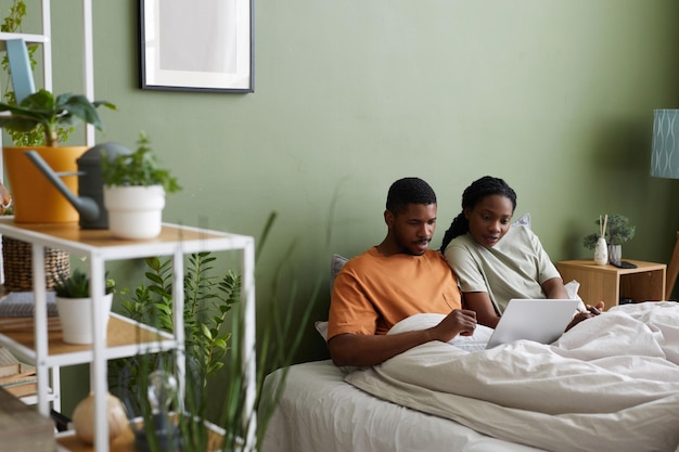 Young couple watching movie on laptop in bedroom