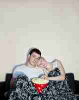Photo young couple watching television and eating popcornxa