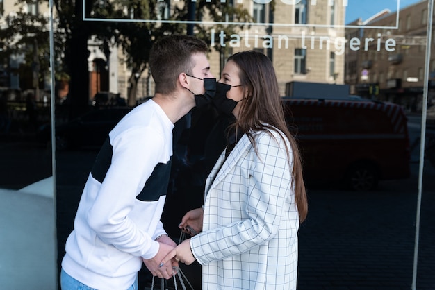 Young couple wearing protective face masks and kiss each other. Quarantine