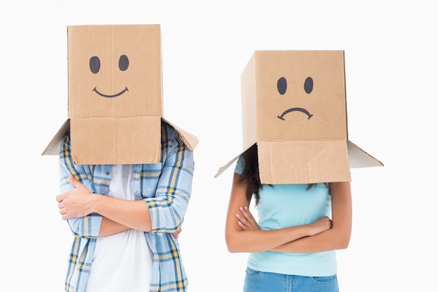 Young couple wearing sad face boxes over head