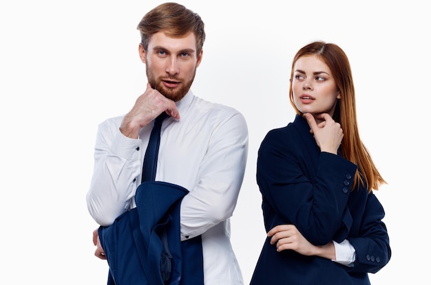 Молодая пара в костюмах стоит рядом с коллегами по работе, общающимися по финансам