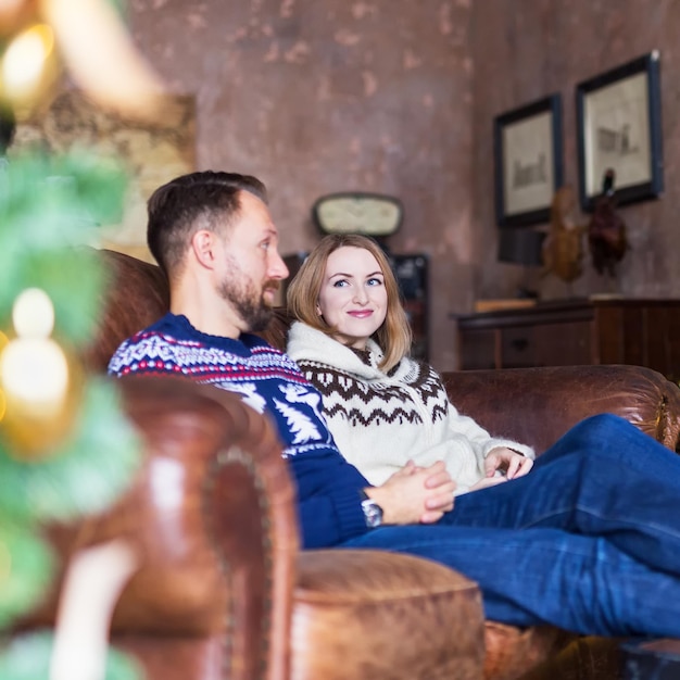 Young couple wearing warm jerseys while relaxing on the sofa in the loft