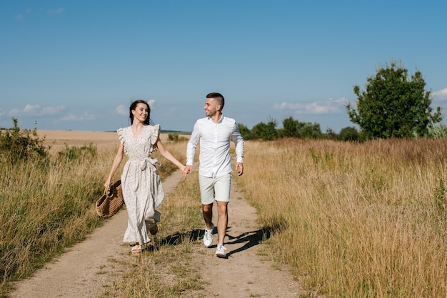 Young couple in the wheat field on sunny summer day. Couple in love have fun in golden field. Romantic couple in casual clothe outdoodrs on boundless field