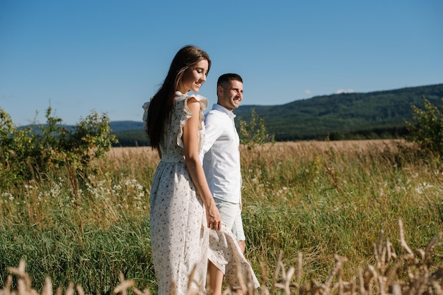 Photo young couple in the wheat field on sunny summer day. couple in love have fun in golden field. romantic couple in casual clothe outdoodrs on boundless field