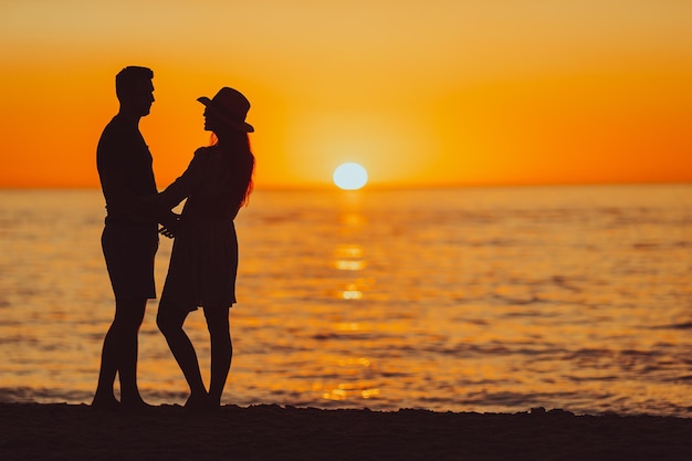 Giovane coppia sulla spiaggia bianca durante le vacanze estive al tramonto foto fuori fuoco