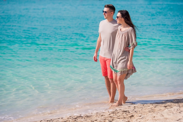 Young couple on white beach during summer vacation. Happy family enjoy their honeymoon