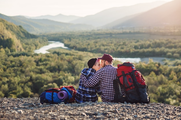 山で一緒に旅行するバックパックと若いカップル。