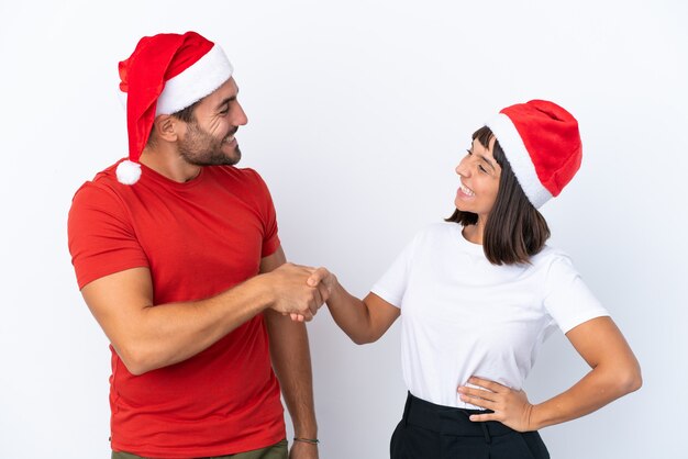 Молодая пара в новогодней шапке на белом фоне, рукопожатие после хорошей сделки