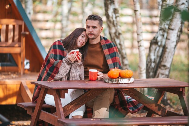 Young couple with coffee in their backyard during autumn