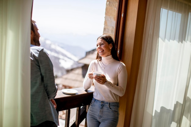 Young couple with cups of hot tea at the winter window