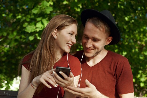 young couple with earphones and a phone in a park