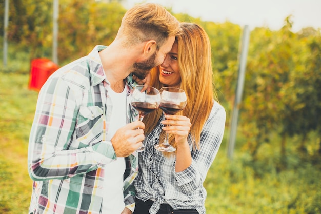 Young couple with glasses of red wine in the vineyard