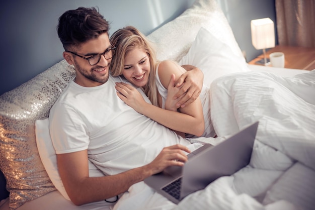 Молодая пара с ноутбуком в постели