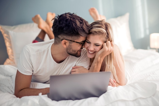 Young couple with laptop in the bed