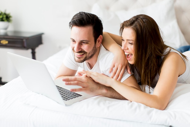 Young couple with laptop in the bed