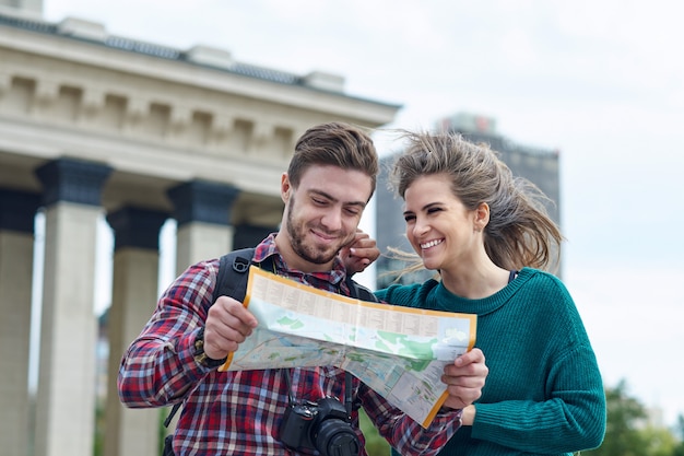 Young couple with a map in the city. Happy tourists sightseeing city with map