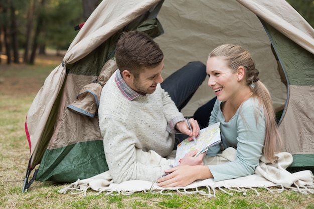 Young couple with a map lying in tent