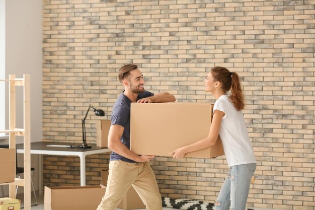 Young couple with moving box at new home