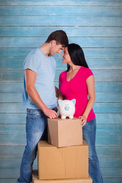 Young couple with moving boxes against wooden planks