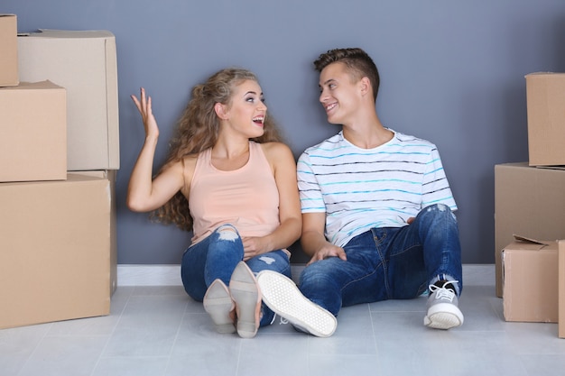 Young couple with moving boxes on floor in room at new home