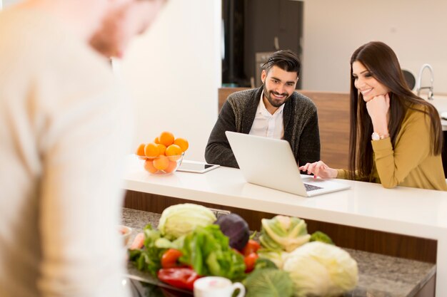 Young couple working on laptop in the kitchen