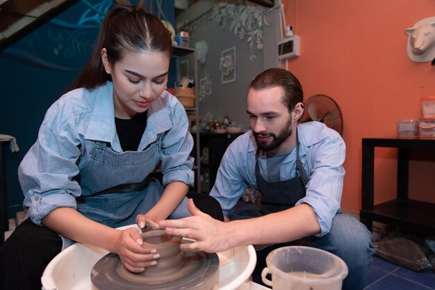 写真 粘土 の 刻 を 作る こと を 楽しむ 若い 夫婦 たち 陶器 を 用い,粘土 から 花瓶 を 作る の を 互い に 助ける