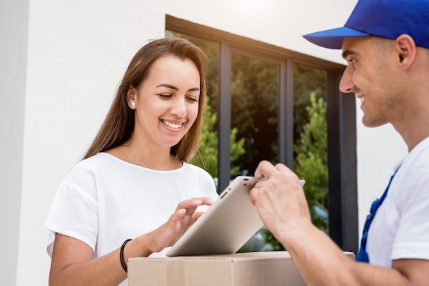 Young courier delivering goods to a young woman at home