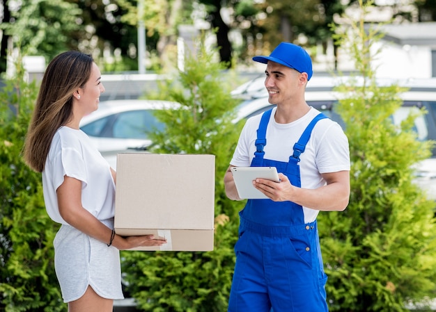 Young courier delivering goods to a young woman at home