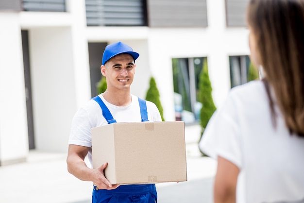 Young courier delivering goods to a young woman at home