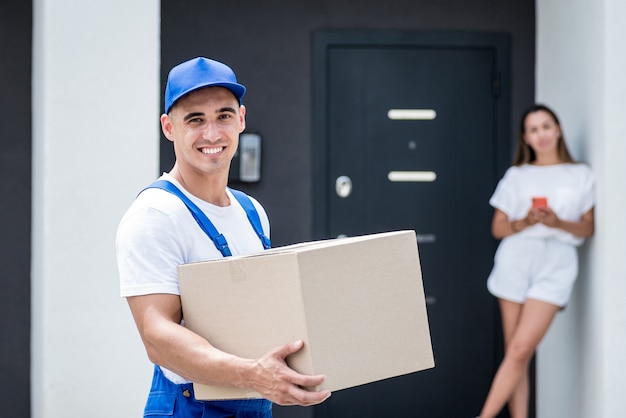 Young courier delivering goods to a young woman at home