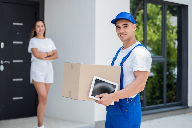 Young courier delivering goods to a young woman at home
