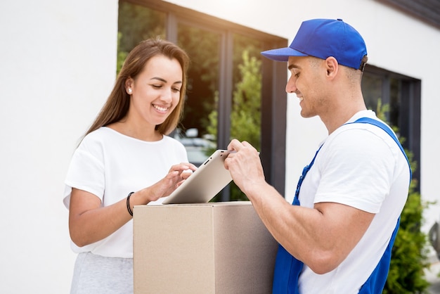 Young courier delivering goods to a young woman at home